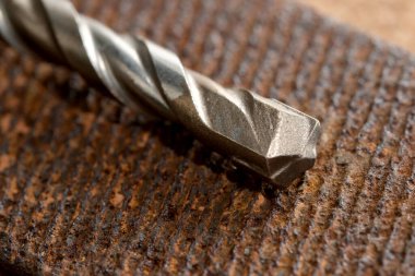 Yıpranmış ahşap üzerindeki metalik matkap ucu dizaynını ön plana çıkarır..