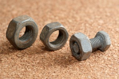 Üç metalik bağlayıcı bir mantar yüzeyde duruyor, endüstriyel tasarımlarını sergiliyorlar..