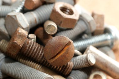 Metal vidalar, cıvatalar ve fındıklar aşınmış cazibelerini ışıkta sergilemek için birbirine karışmış..