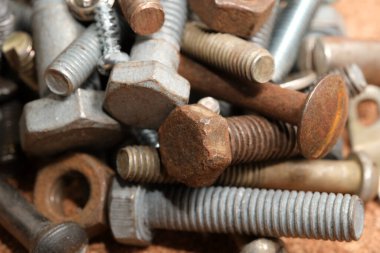 Çeşitli civata ve fındıklardan oluşan bir kolleksiyon ahşap bir tezgahta gelişigüzel yatıyor..