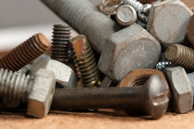 Metal civatalar, fındıklar ve vidalar ahşap gösterisine saçılmış..