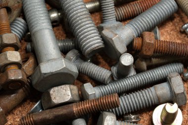 Çeşitli metal cıvatalar, fındıklar ve yıkamacılar kırsal bir tezgah alanı düzenliyor..