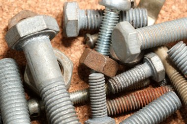 Türlü vida ve cıvata koleksiyonu desenli bir mantar tahtada duruyor..