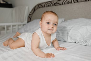 Yeni doğmuş mutlu bebek yatakta uzanıyor ve gülümsüyor. Mutlu bir aile. Parlak gözler. Çocuk düşünüyor..