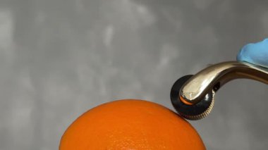 Kozmetik Derma Roller turuncu bir Cilt Konsepti üzerinde yuvarlanıyor. Dermaroller