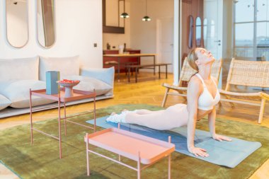 Beyaz kadın spor giyim eğitimi alıyor, yoga egzersizi yapıyor.