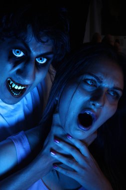 Kurbanını boynundan tutan bir vampirin cadılar bayramı görüntüsü.,