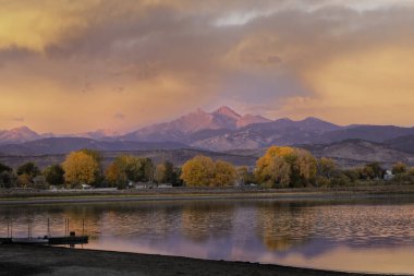 A beautiful fall sunrise along a Colorado lake with Longs Peak glowing in the distant clipart