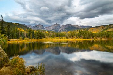 Rocky Mountain Ulusal Parkı 'ndaki Sprague Gölü boyunca sonbahar sezonu. Fırtınalı gökyüzü kıtasal bölünmenin üzerinde süzülüyor.