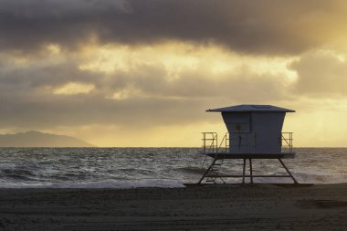 Güneş Huntington Sahili 'ndeki 7 numaralı cankurtaran kulesinde batıyor.