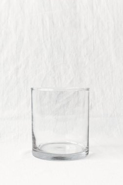 Temiz beyaz desenli arka planda boş, berrak bir bardak ya da bardak. Bu minimalist, yüksek çözünürlüklü görüntü berraklık veya boşluk kavramları için ya da içkiyle ilgili projeler için çok yönlü bir model olarak mükemmeldir..