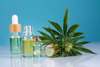 Cam şişelerdeki kenevir yağı kenevir yaprağı ve hafif arka planda kenevir yağı ile bir şişe kenevir yağı.