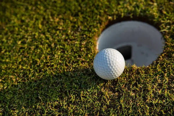 Golf topunu yeşil çimlerde bir golf deliğinde.