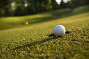 Golf topunun ve golf sahasındaki bulanık arkaplanlı yeşil golf sahasının yakınına..