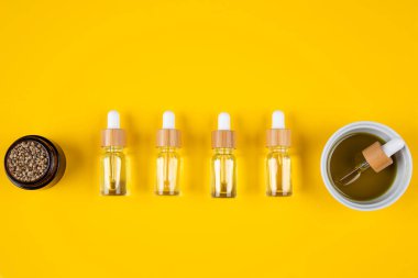 Sarı arka planda farklı renkte serum ve pipet şişeleri. en üstteki görünüm