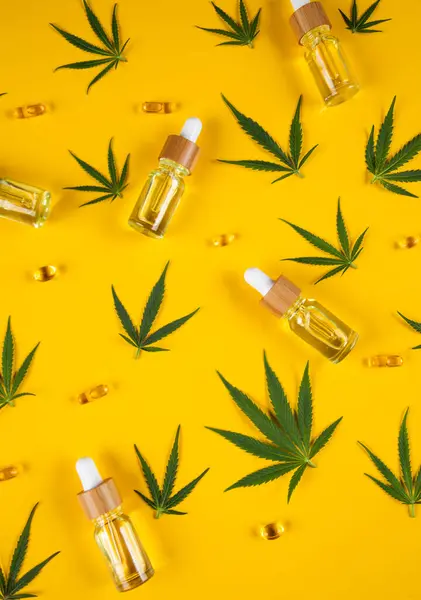 黄色い背景の大麻の葉およびマリファナのオイルが付いている大麻のオイル ボトル 平らな層 — ストック写真