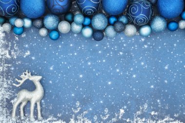 Ren geyiği süsü ve grunge 'da parlak mavi ağaç süslemeleri olan bir Noel arkaplanı. Bayram sezonu için büyülü kuzey kutbu soğuk kış teması
