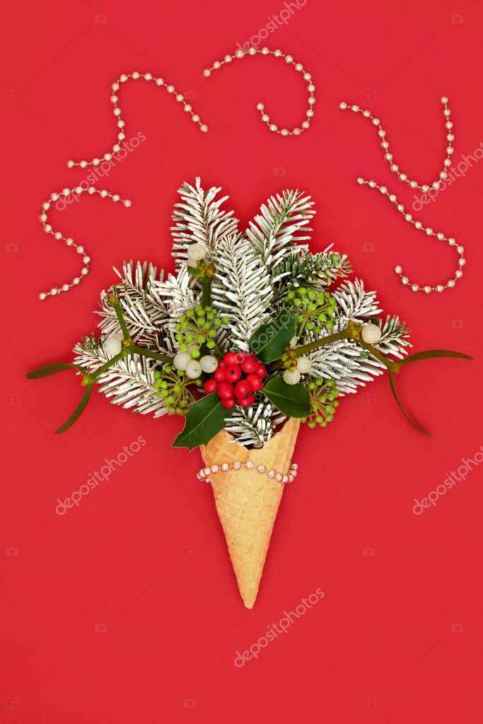 Christmas party time surreal ice cream waffle cone concept with snow covered fir, gold beads, winter greenery on red. Festive nature abstract fun design for Xmas holiday and New Year.