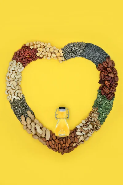 Healthy heart food high in lipids containing essential fatty acids unsaturated good fats for low cholesterol levels with nuts, seeds and olive oil. Wreath on yellow background.