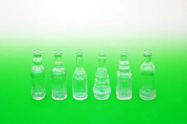 Go green use recycled glass bottles not plastic concept with line of old retro glass bottles on gradient green white background. Save the planet, sustainable abstract composition.