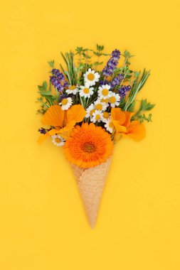 Yenebilir yaz çiçekleri ve dondurmalı waffle külahında taze otlar canlı sarı arka planda minimum gerçeküstü yiyecek konsepti. Kopyalama alanı oluştur.