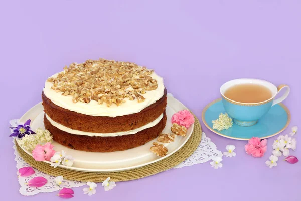 紫色の背景にティーカップと夏の花とアフタヌーンティーのためのニンジンとクルミのケーキ 誕生日パーティーや母の日のための自家製おいしい料理のコンセプト — ストック写真