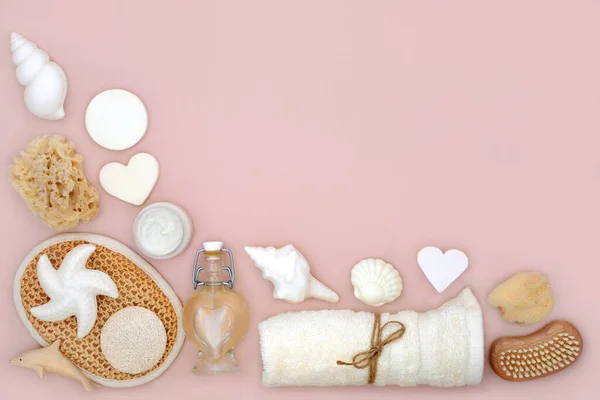 Natural skincare bath accessories for beauty treatment on pink background with assorted body care products for radiant skin and decorative seashell soaps.