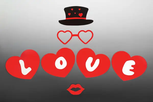 Romantic Valentines Day love design with letters on red heart shapes, with luscious lips, glasses and black hat. Surreal valentine lovers concept on gradient gray white.