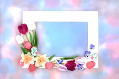 Pastel mavi ve pembe gökyüzü bulutu üzerinde yumurta ve bahar çiçekleri olan Paskalya arkaplan çerçevesi. Beyaz çerçeveli bahar ve tatil sezonu için doğal renkli tasarım.