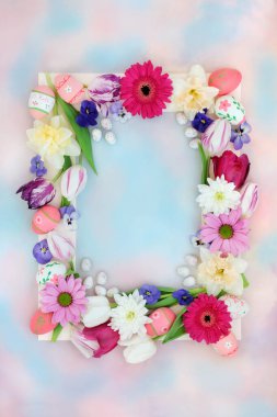 Süslü Paskalya arkaplan sınırında yumurtalar, pastel mavi gökyüzü arka planında çiçekler. Tatil ve Bahar mevsimi için doğal çerçeve tasarımı.