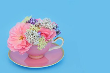 Sürreal gül, kediotu, lavanta ve yaşlı çiçekler çay fincanında mavi. Eğlenceli bitkisel ilaç düzenlemesi. Çiçeklerin adaptojen gevşemesi sağlık faydalarını sakinleştirir..