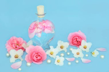 Rosewater for skincare with rose and orange blossom  flowers, heart shaped bottle and pearls on blue. Balances natural skin oils, reduce redness, naturally hydrates skin. clipart