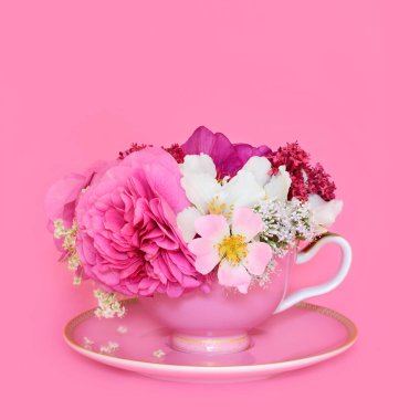 Yaz çiçeği aranjmanı pembe arka planda çay fincanında. Doğal alternatif bitkisel ilaç içeceği. Anksiyete ve stres giderici. Gerçeküstü yemek sanatı.
