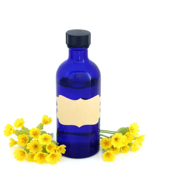 stock image Cowslip flowers essence blue  bottle on white. Used in herbal medicine to treat digestion, respiratory, skincare and stress problems. Primulaceae.