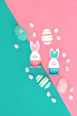 Paskalya tavşanı ve yumurta soyut kompozisyonu. Eğlenceli semboller, pembe mavi köşegen üzerinde tatil sezonu için yenilebilir tatlı yiyecek şekeri tasarımı.