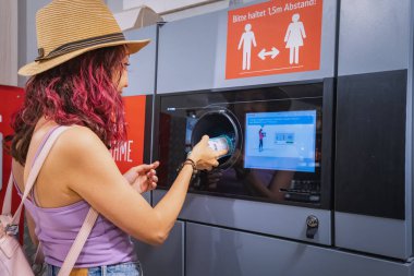 25 Temmuz 2022, Munster, Almanya: Öğrenci bir kız otomatik makineye geri dönüşüm için plastik bir içecek şişesi verdi. Çevre dostu yaşam tarzı ve nakit para