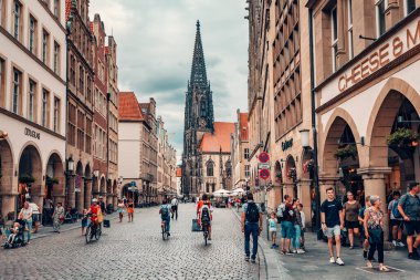 25 Temmuz 2022, Munster, Almanya: Prinzipalmarkt - ünlü alışveriş caddesi ve turistik merkezde turist kalabalığı. Arka planda Saint Lamberti Kulesi.