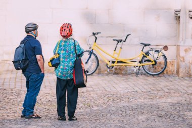 25 July 2022, Munster, Germany: An elderly senior couple arrived on a tandem bicycle and explore the sights of the old town clipart