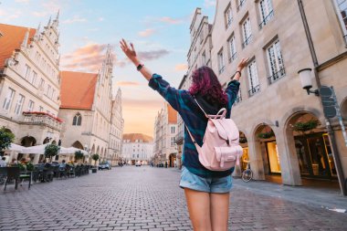 Prinzipalmarkt caddesini ziyaret eden mutlu turist kadın ve Munster, Almanya 'daki eski kasaba mimari binalarına hayran.