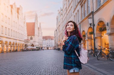 Prinzipalmarkt caddesini ziyaret eden mutlu turist kadın ve Munster, Almanya 'daki eski kasaba mimari binalarına hayran.
