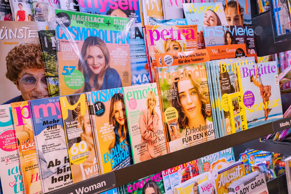 25 July 2022, Munster, Germany: A lot of fashion magazines, tabloids and high quality journals on the store counter in German