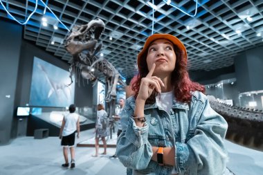 26 Temmuz 2022 'de, Munster, Almanya: Gezintideki heyecanlı turist kız Doğa Tarihi Müzesi' ndeki bir dinozor iskeletinin fosilleşmiş kalıntılarına düşünceli bir şekilde bakıyor.