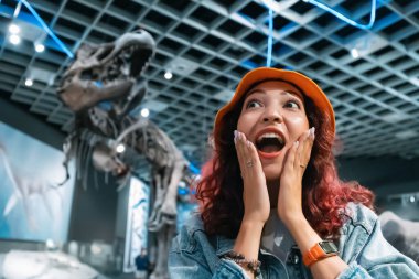 26 Temmuz 2022 'de, Almanya' nın Munster kenti: Gezideki heyecanlı turist kız, Doğa Tarihi Müzesi 'ndeki bir dinozor iskeletinin fosilleşmiş kalıntılarına ilgi gösteriyor.
