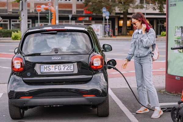 stock image 26 July 2022, Munster, Germany: A girl charges her Smart car for two in a free parking lot for eco-electric cars in the city