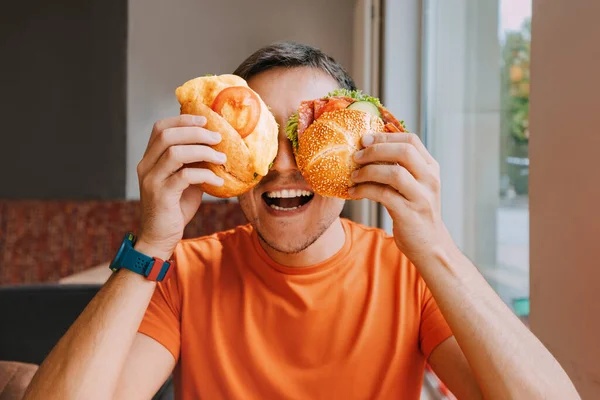Щасливий Чоловік Їсть Два Гамбургери Або Бутерброд Апетитом Кафе Швидкого — стокове фото
