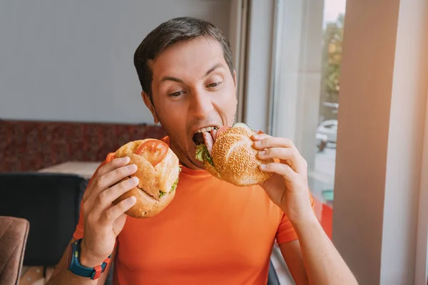 快乐的男人在快餐店里吃着两个汉堡包或三明治 — 图库照片