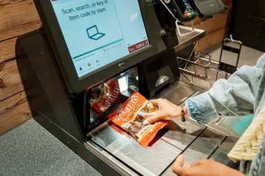 30 Temmuz 2022, Köln, Almanya: Kız müşteri taramaları ve otomatik self-servis kontrol terminalinde süpermarketten gelen mallar için ödeme