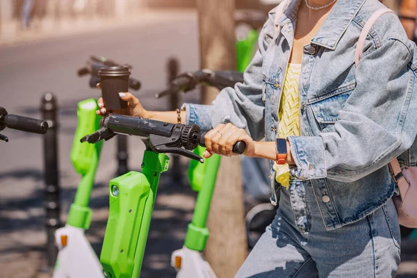 Kız şehirde dolaşmak için elektrikli scooter kiralıyor. Çevre taşımacılığını ve çağdaş hareketliliği seçin