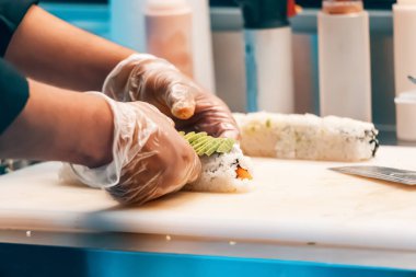 Şef eldiven giyer restoranda suşi pişirir.