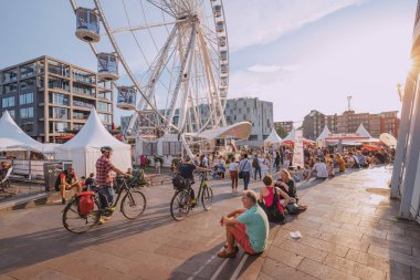 29 Temmuz 2022, Köln, Almanya: İnsanlar ve turistler dönme dolabın yanında dinleniyor. Sokak yemeği festivali. Tatil ve boş zaman